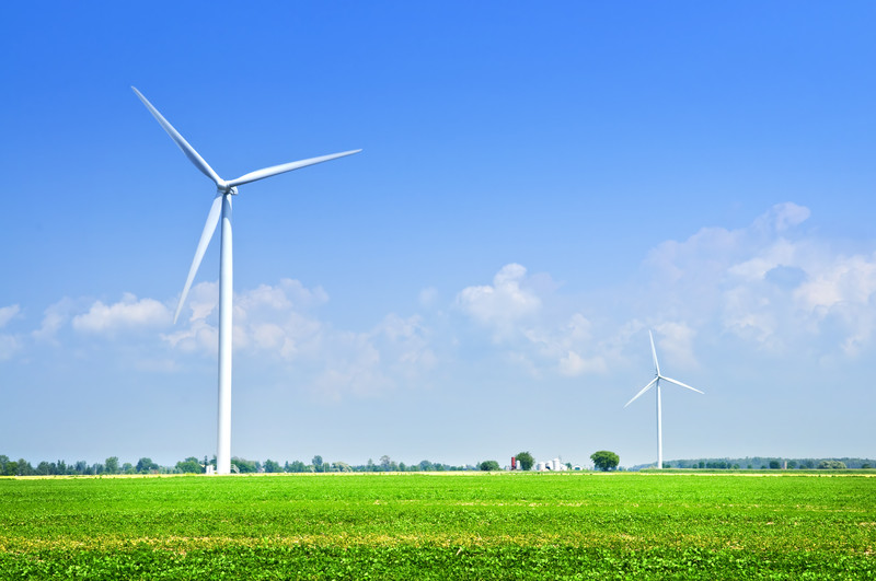 Green field and blue sky with wind turbines